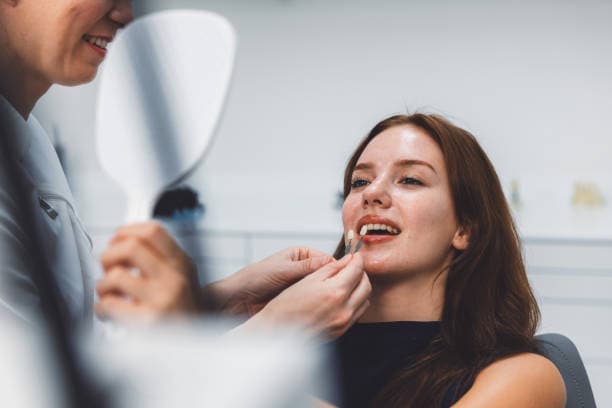 Woman comparing Invisalign aligners and veneers in dental office